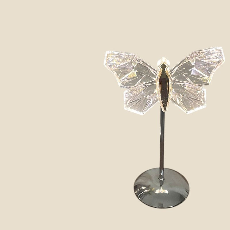 Lampa nocna LED NovaPulse w kształcie kryształowego motyla na metalowej podstawie, emitująca delikatne światło.