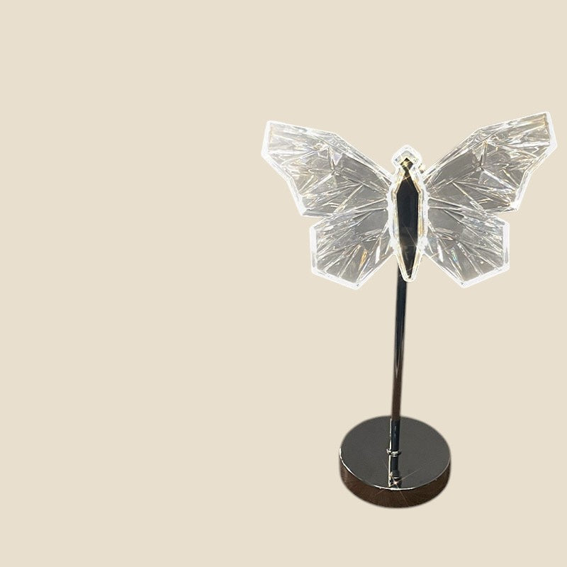 Lampa nocna LED NovaPulse w kształcie kryształowego motyla na metalowej podstawie, emitująca nastrojowe światło.