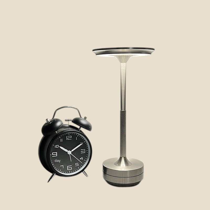 Lampa dotykowa NovaPulse w kolorze srebrnym z aluminiowym kloszem obok czarnego budzika w stylu retro